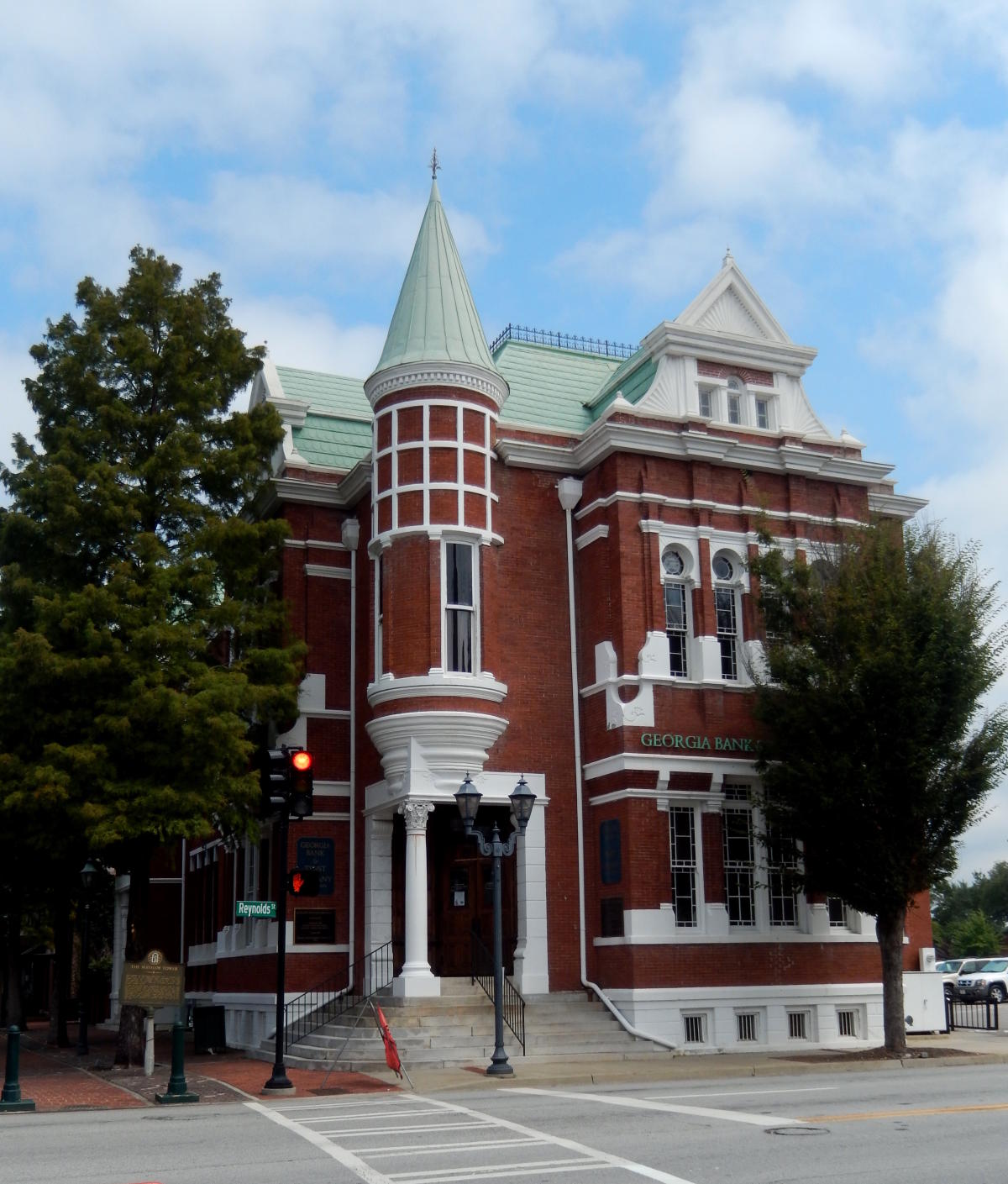 The Augusta Cotton Exchange at 8th & Reynolds in downtown Augusta — the 1886 red-brick building with its green copper corner turret and arched upper windows, seen from the street corner